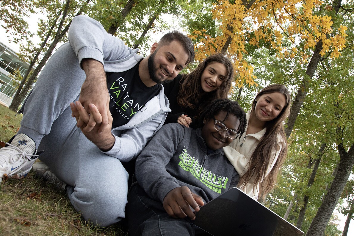 four students outside with laptop on angle