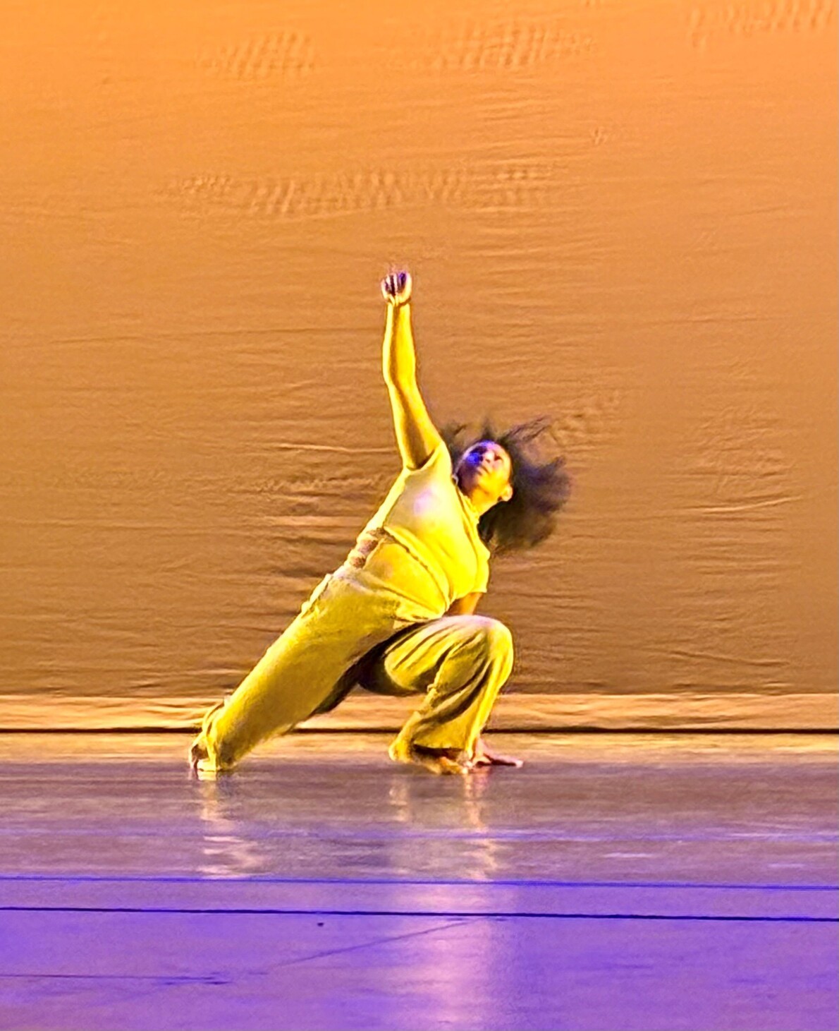 dancer in yellow outfit kneeling on floor