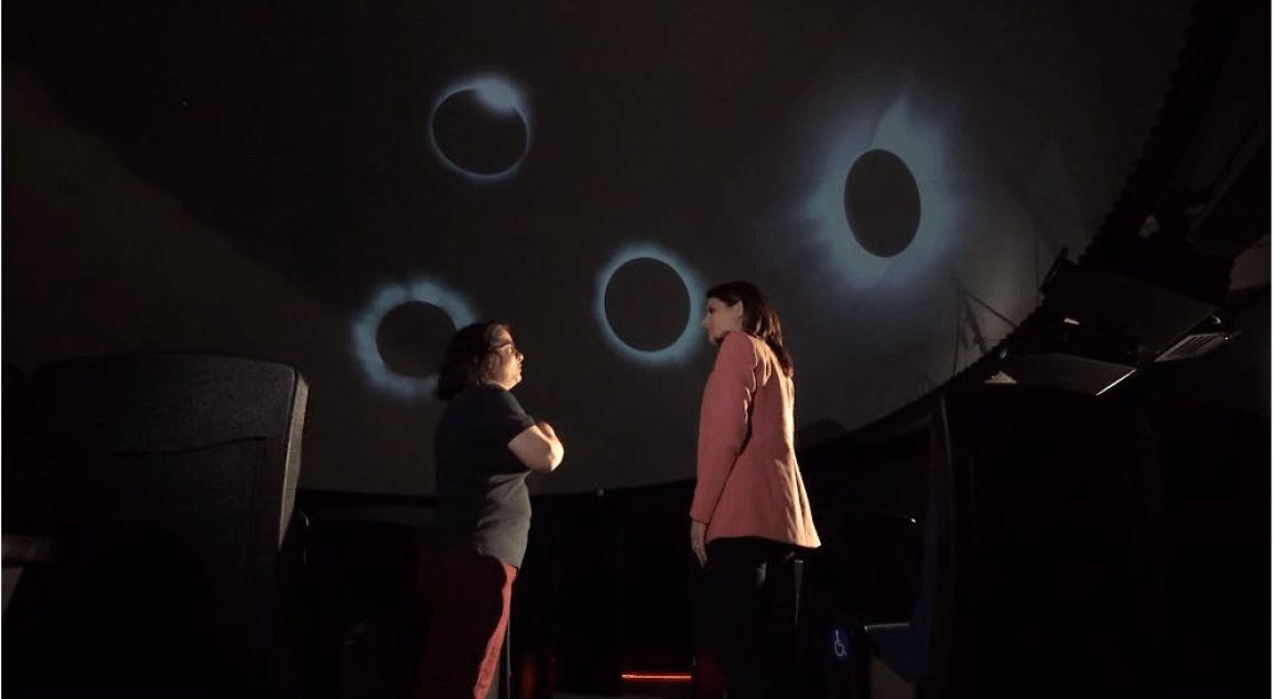 2 women in planetarium with eclipse images