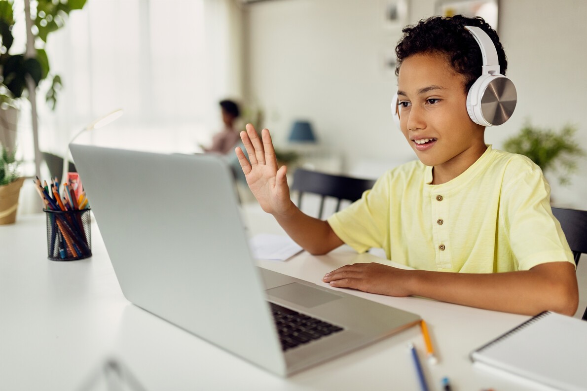 boy in yellow shirt with white headphones with laptop
