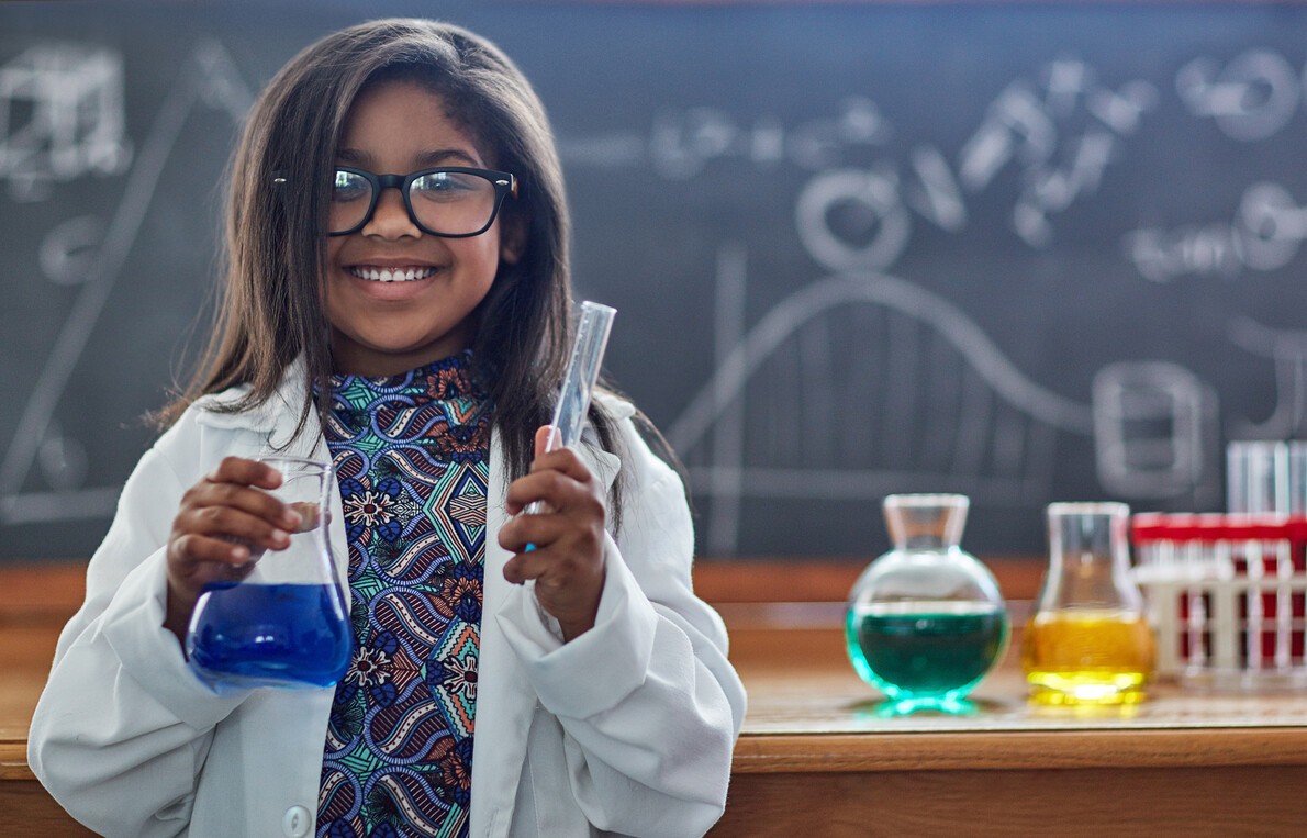 little girl in white lab coat holding glass container with blue liquid