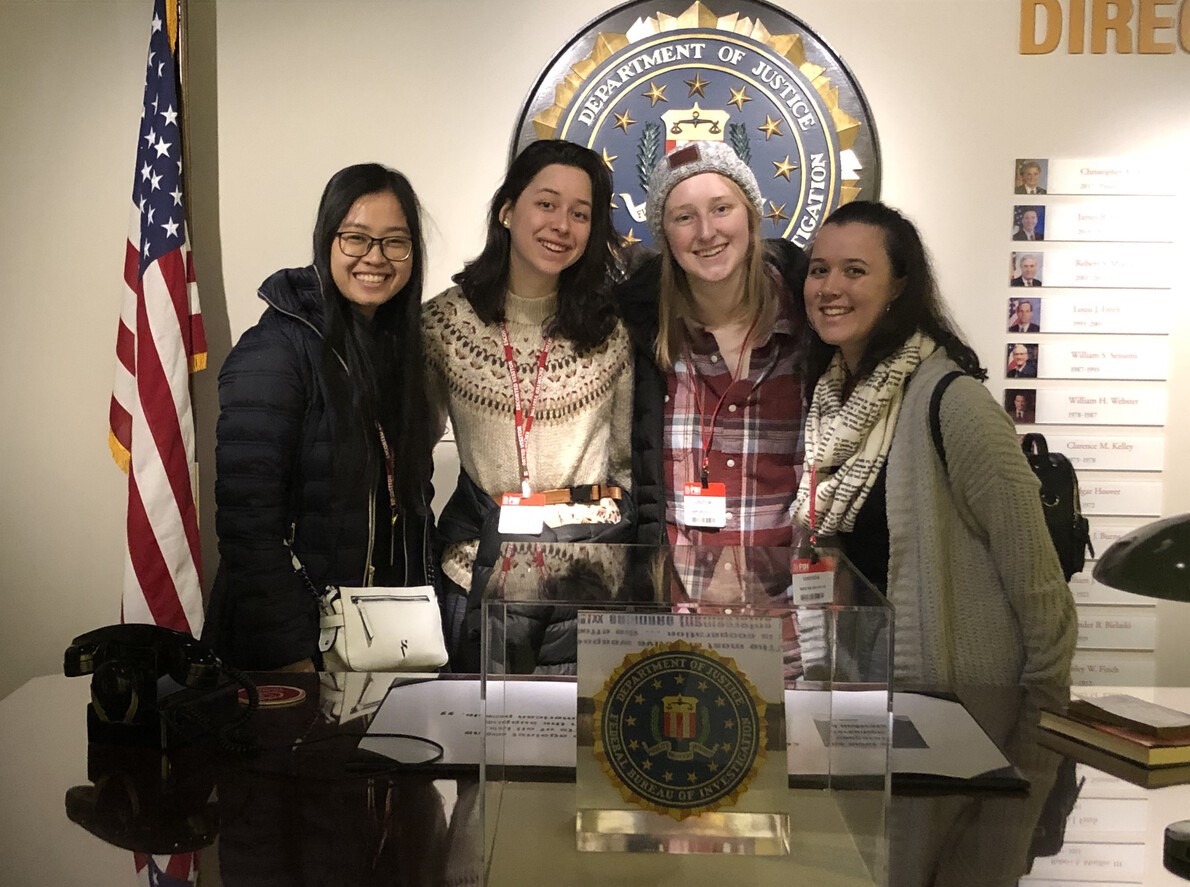 four female students with state seal and flag