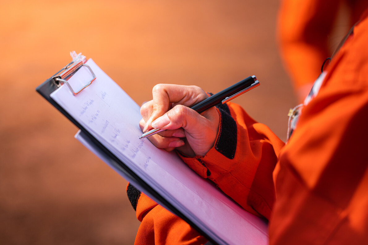 worker in orange suit writing notes on pad