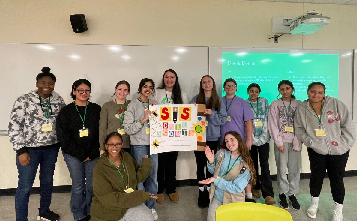 club members and girl scouts with poster