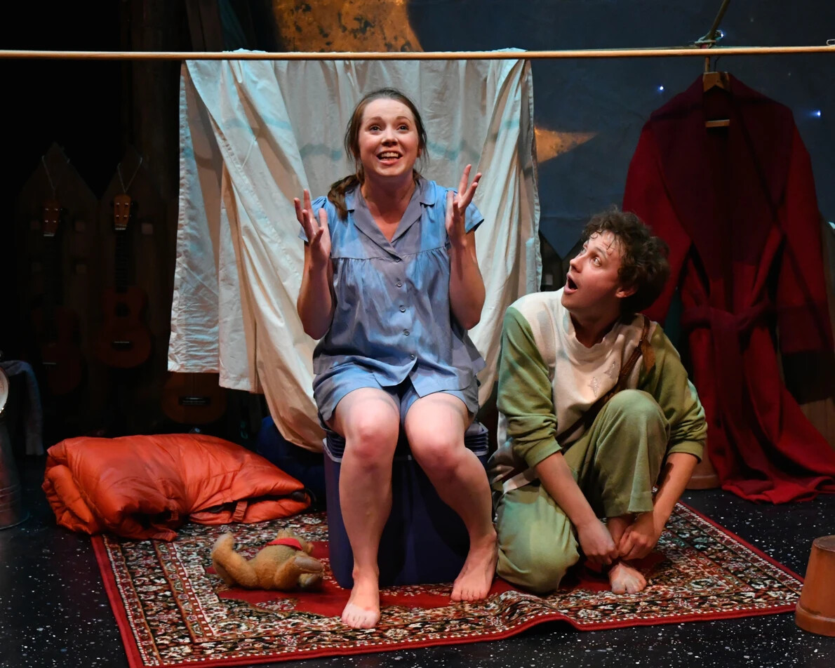 2 performers sitting and kneeling in pjs