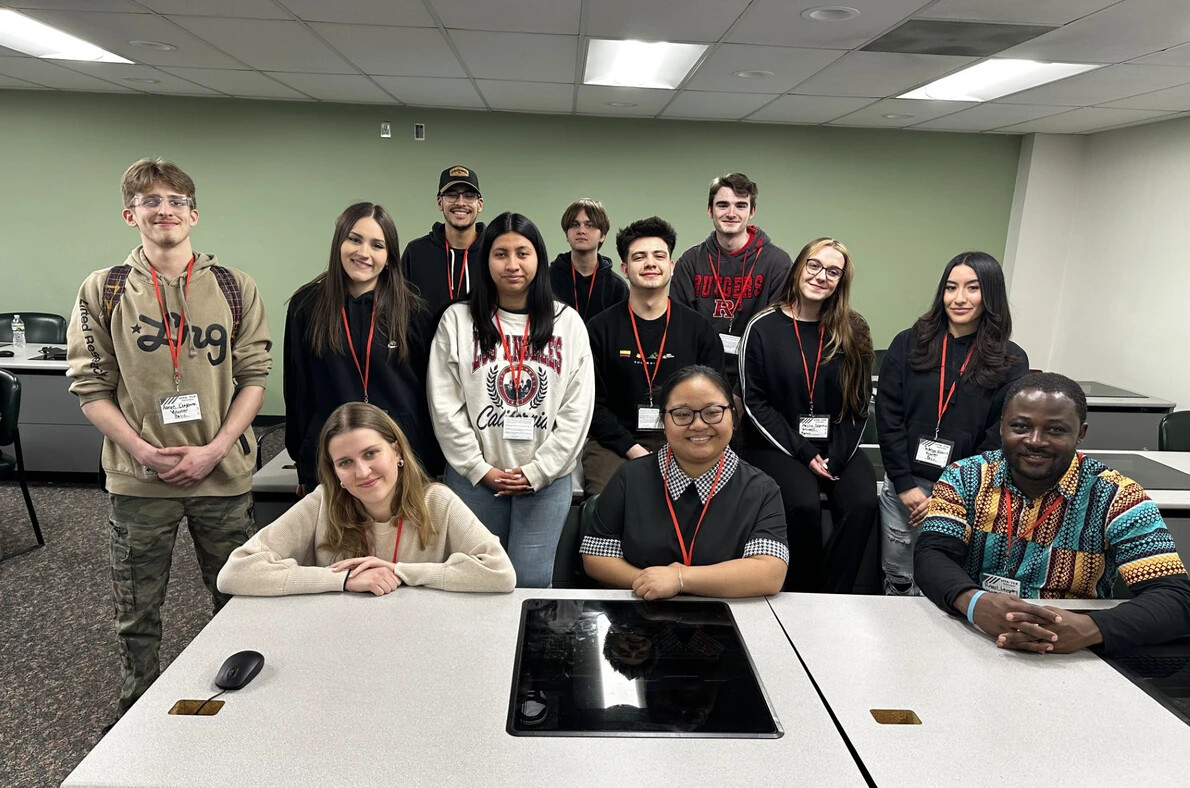 VITA students sitting and standing around table
