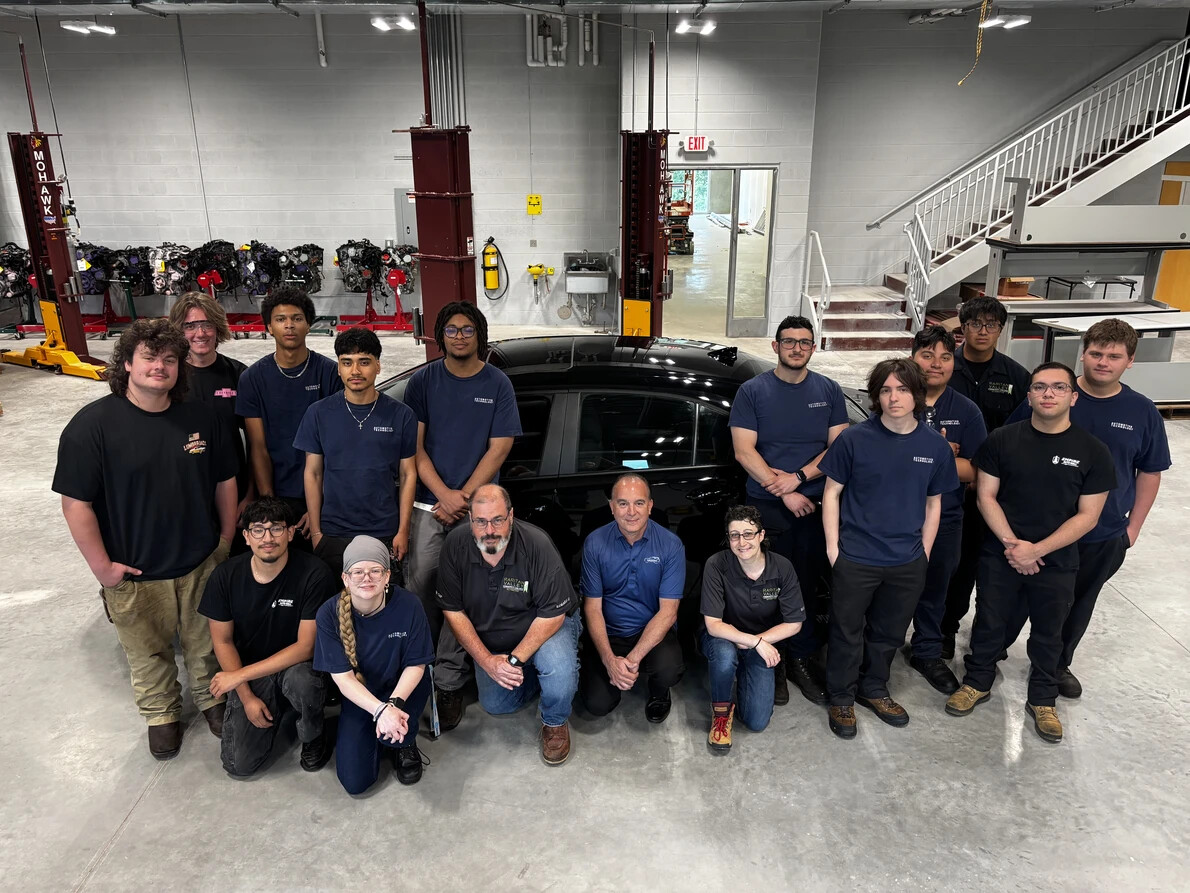 automotive students, faculty in front of dark car