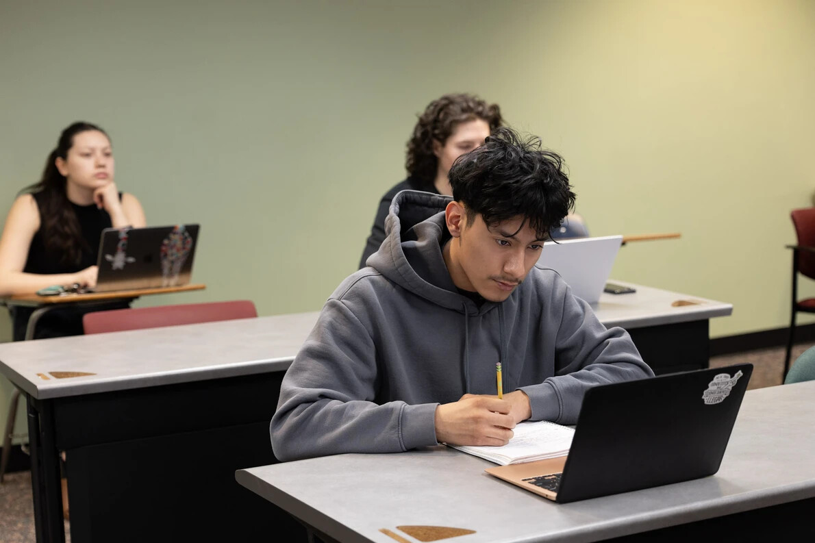 3 students on laptops in classroom