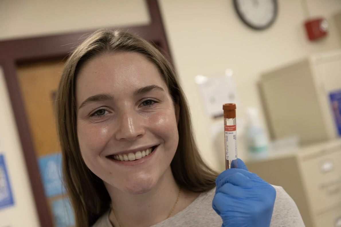 young woman with blue glove holding up test tube