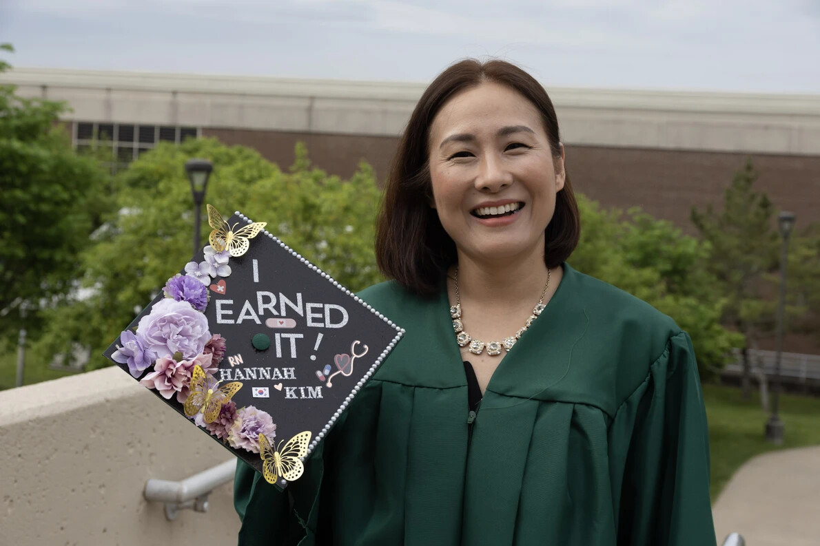 older grad holding cap saying I earned it
