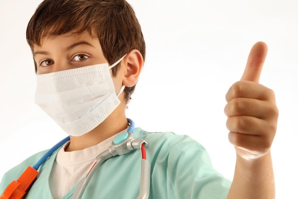 masked child doctor with thumb's up