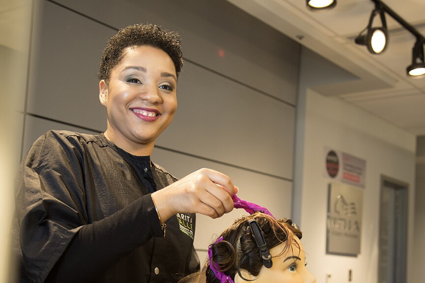 short-brown haired cosmetology student working on manequin