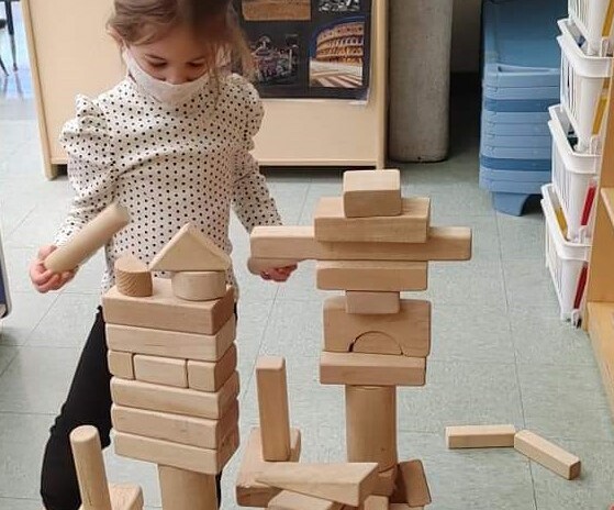 masked child playing with block tower