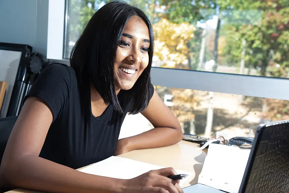 brown-haired female student working on laptop