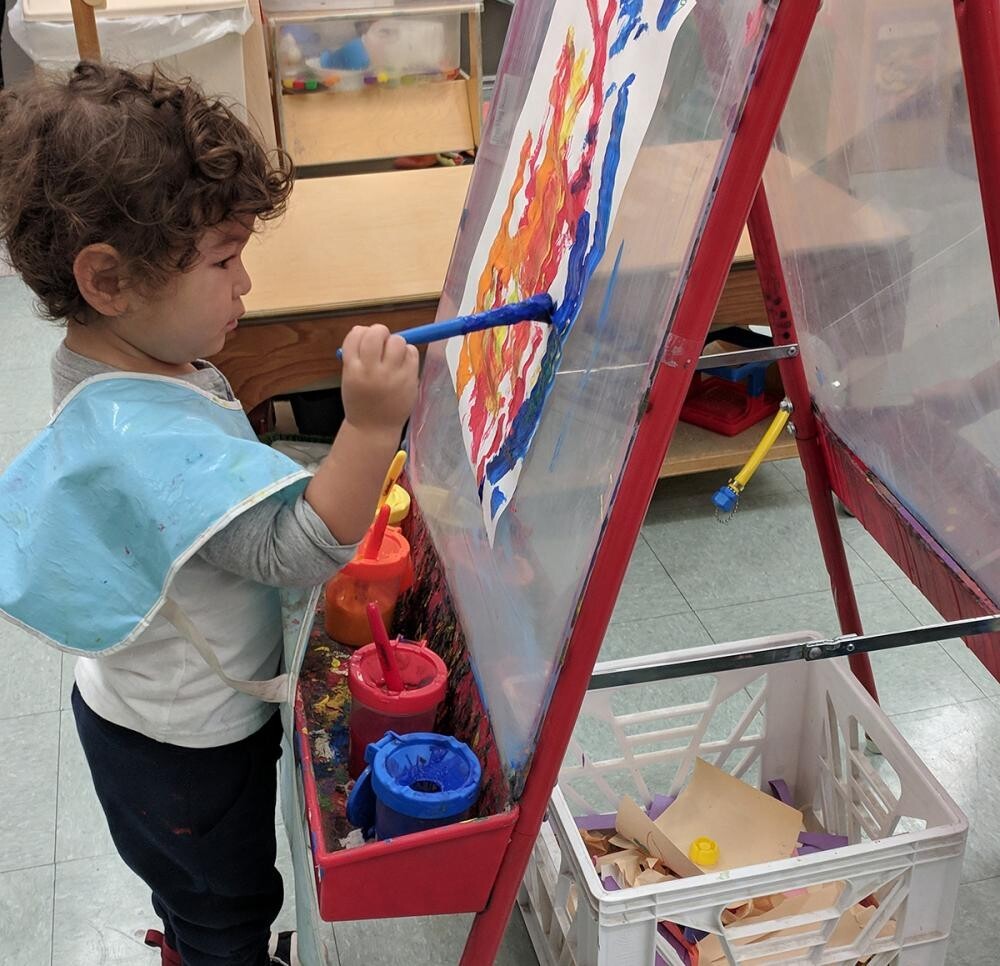 toddler painting at easel