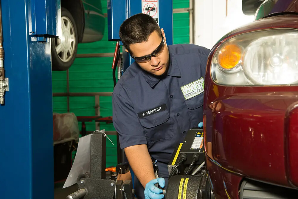 man wearing protective glasses working on red car