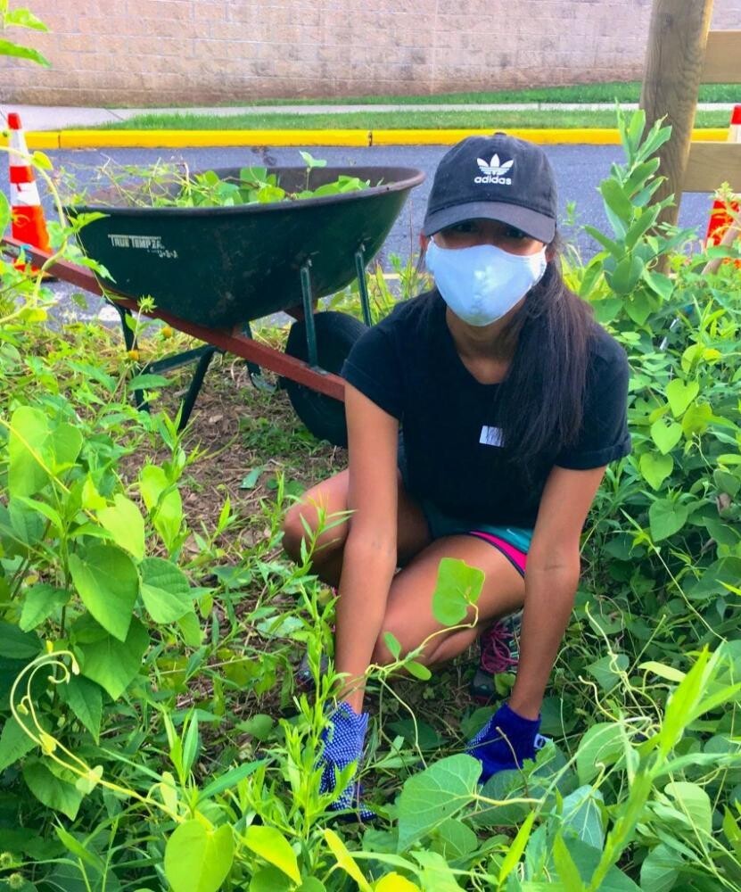masked female student bending and planting