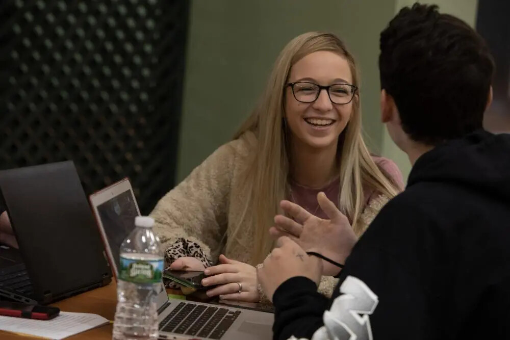 blonde female student and back of male student at laptop