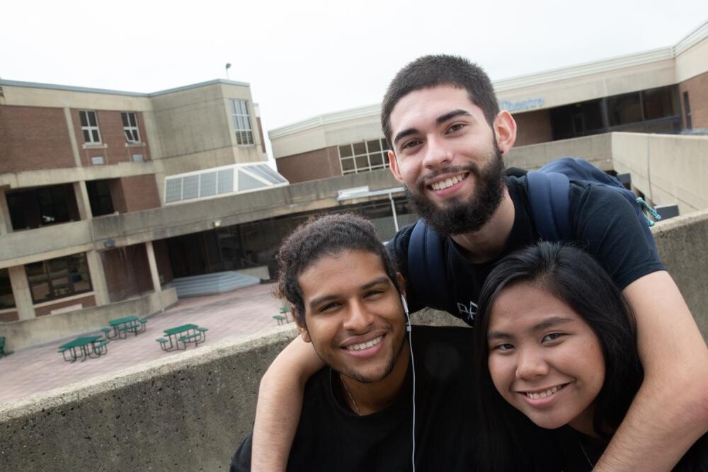 three students outside with patio area behind them