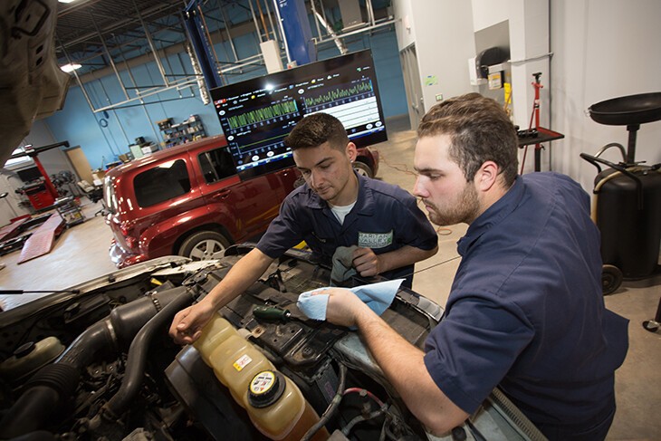 2 males students working on car