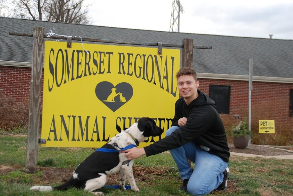male student with dog outside animal shelter