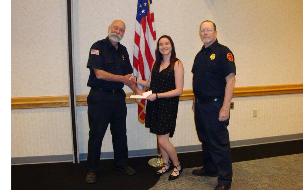 girl getting scholarship from fire police members