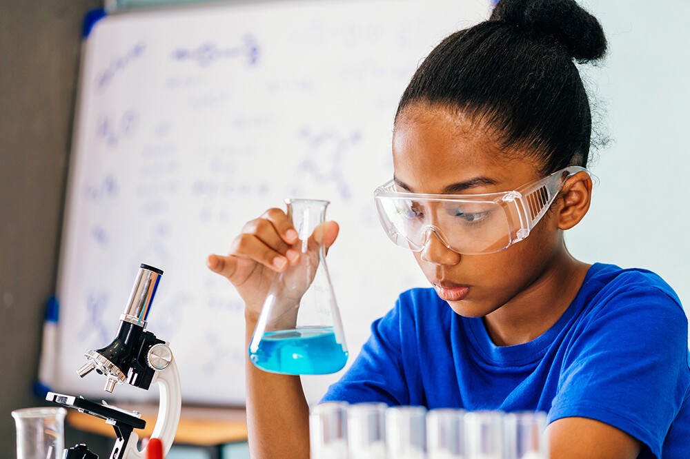 girl in protective glasses doing science experiment