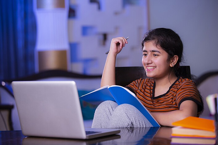 teen girl with orange and black striped shirt on laptop