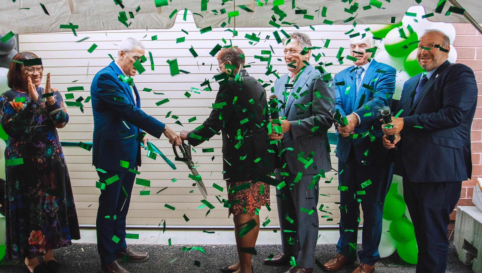 siz people and lots of confetti at a ribbon cutting