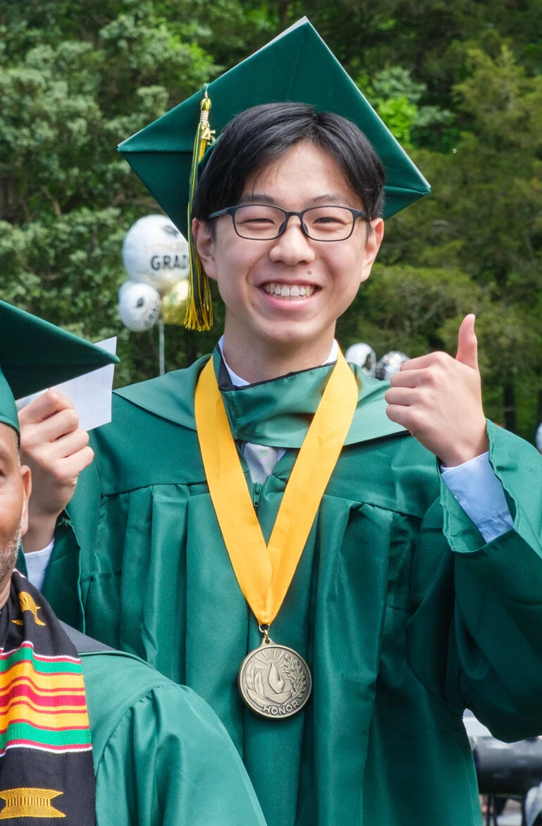 graduate smiling, giving a thumbs up, wearing a metal