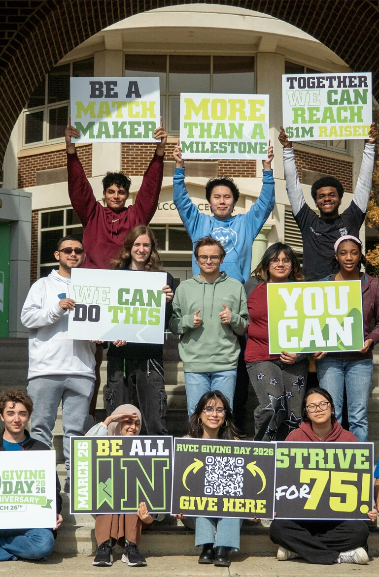 Group of students standing outside holding up signs to promote Giving Day donations