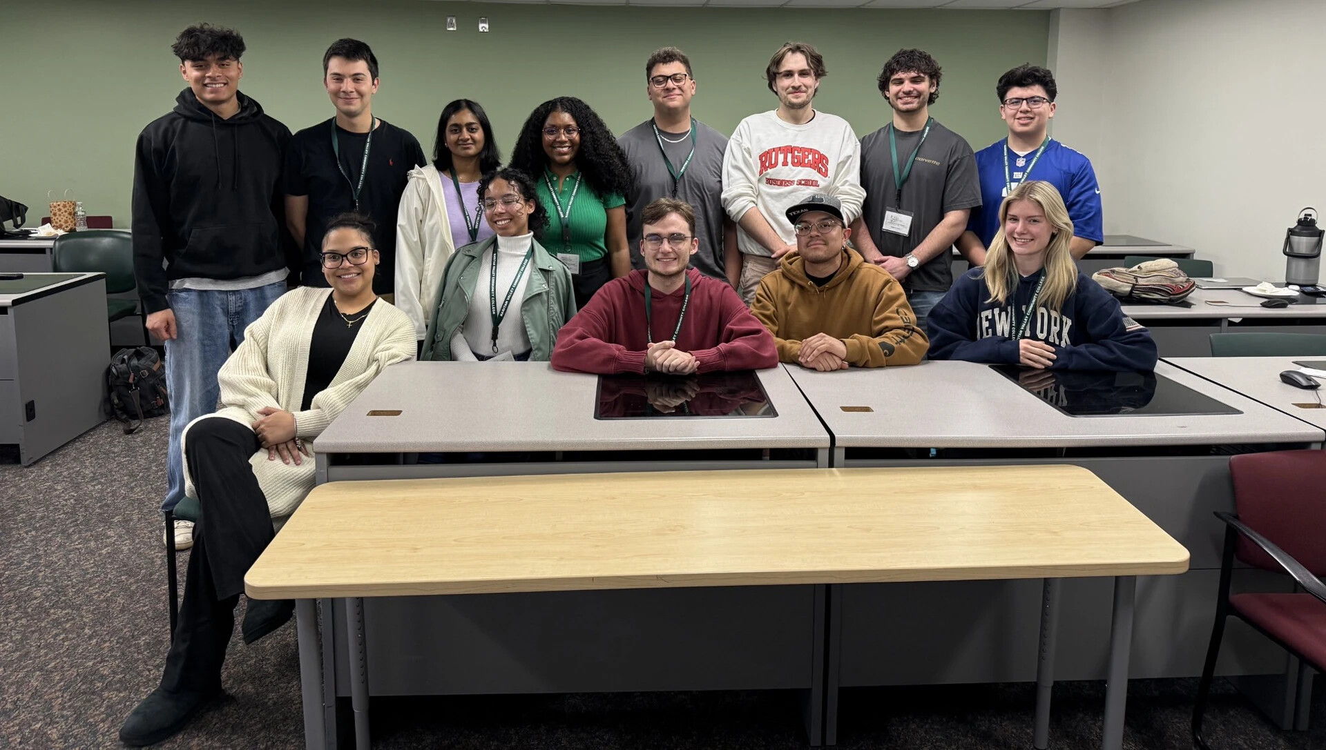 Group of college students wearing various colored sweatshirts lined up osing for a photo
