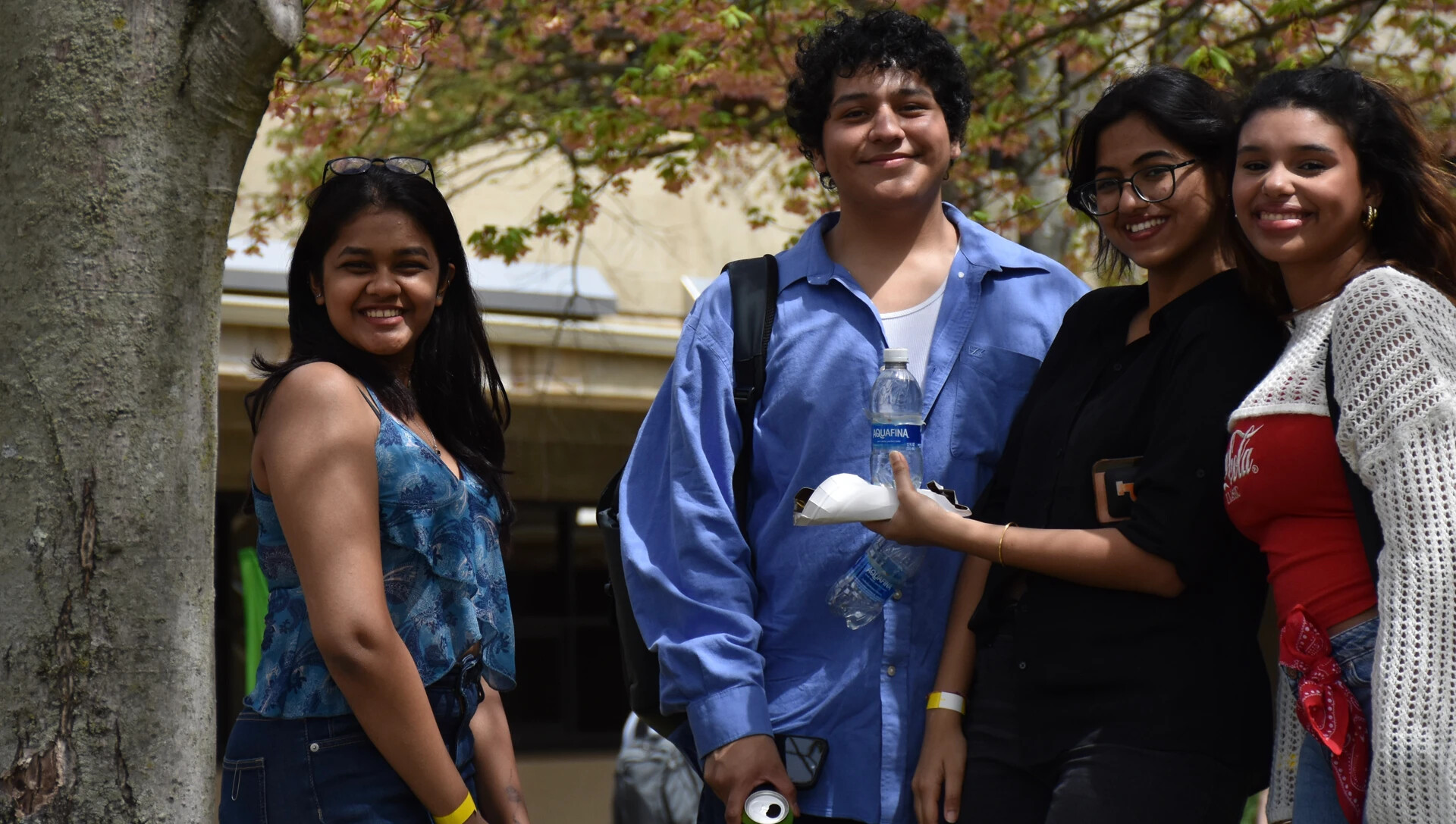 4 students outside under the trees, smiling