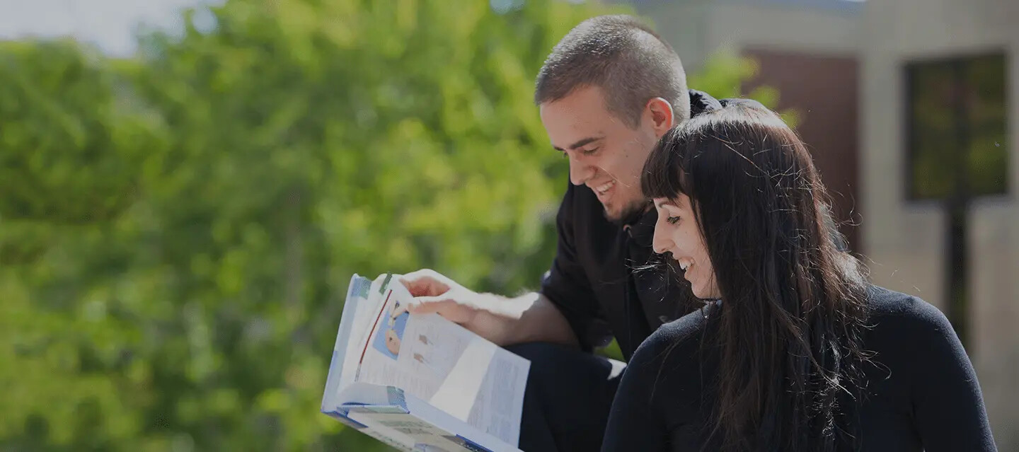 Two students reviewing work outside