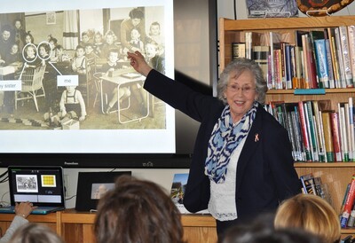 maude dahme in classroom pointing to photo