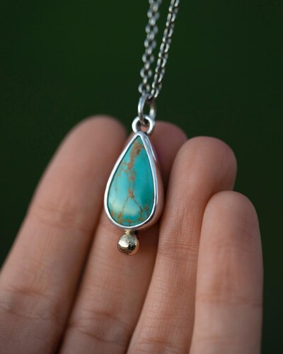 turquoise pendant in front of hand