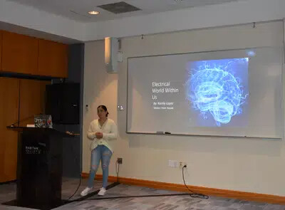 karely lopez standing next to powerpoint slide on screen