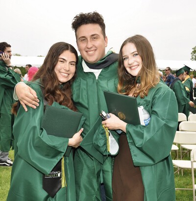 2 female grads with male grad in middle 