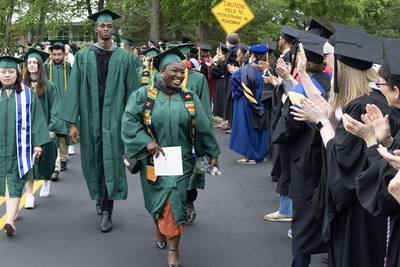 grads walking as professor applaud on right