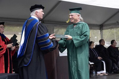 mike giving diploma case to older male grad