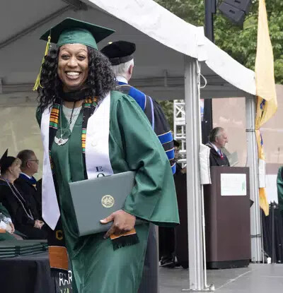 single older female grad on stage smiling