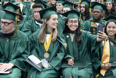 grads in chairs with one taking selfie
