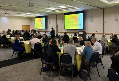 tables of people in conference room with screens