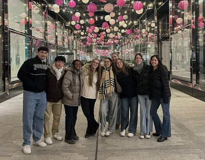 group of students with decorative balls above them in glass lined hallway