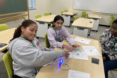 2 girl scouts and rvcc student working on project on table