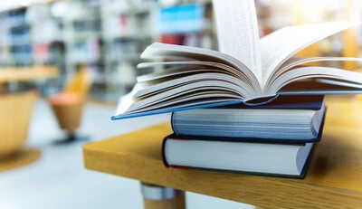 book open on top of other books on table