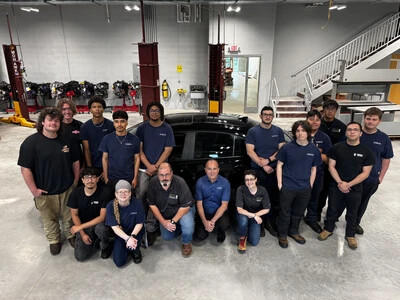 automotive students, faculty in front of dark car