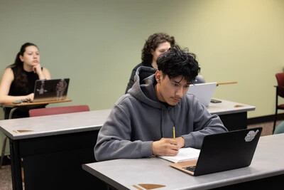 3 students on laptops in classroom