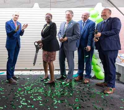 five people standing with one holding very large scissors