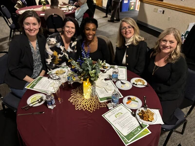 5 women sitting at table with flyers